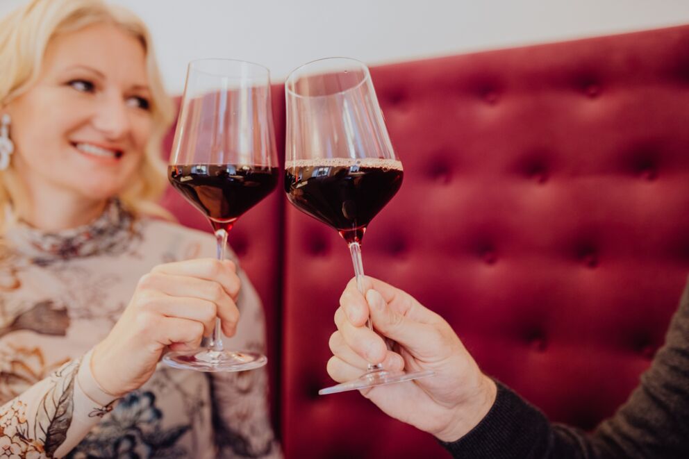 Eine Frau und ein Mann stoßen mit Weingläsern in der Castello Bar im Salzkammergut an.