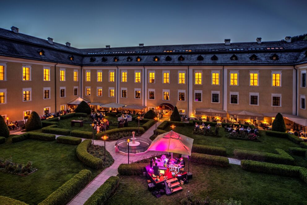 Stimmungsvolle Abendaufnahme im Schlossgarten des Schloss Mondsee mit warmem Licht und ruhiger Atmosphäre