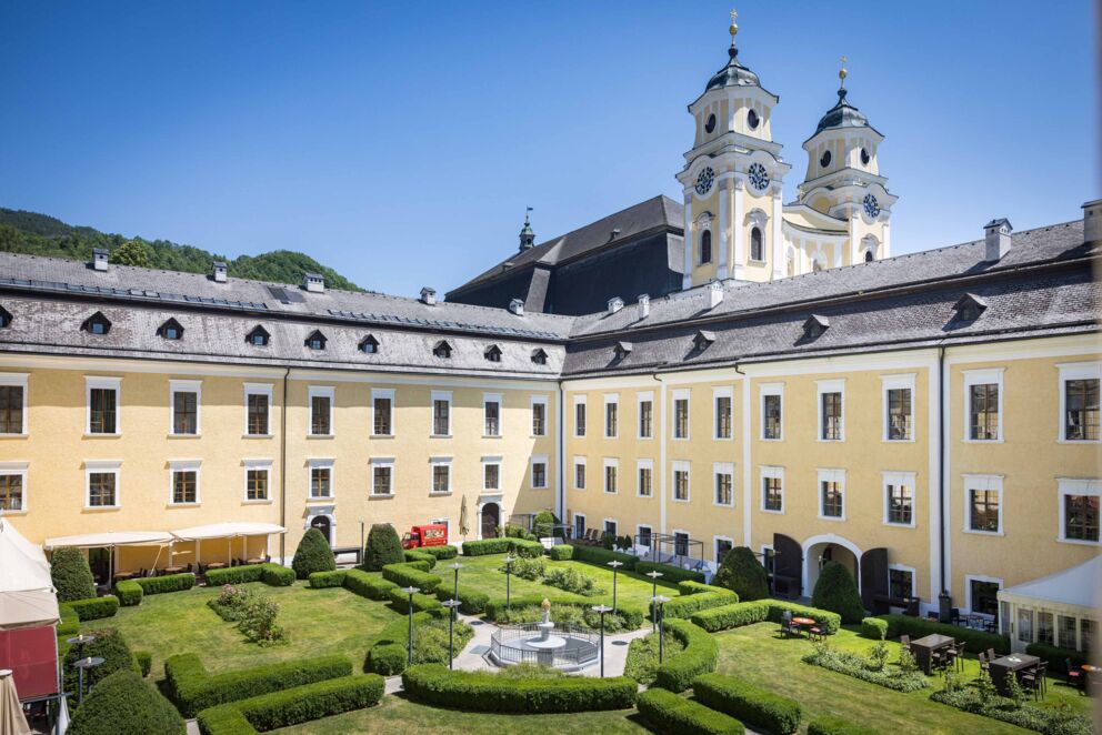 Schlossgarten des Schlosshotels Mondsee mit Blick auf die historische Basilika Kirche – idyllische Kombination aus Gartenanlage und beeindruckender Architektur
