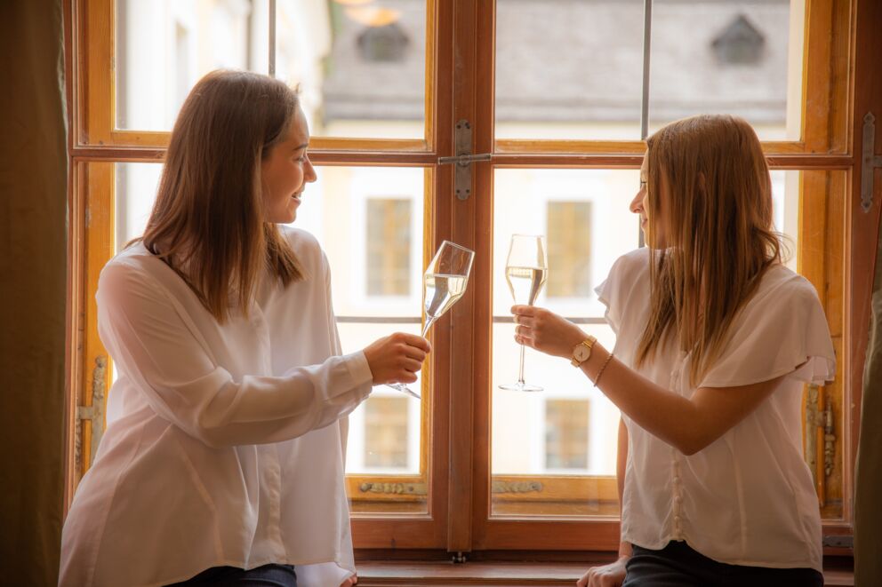 Mitarbeiterinnen Lisa und Antonia stoßen fröhlich im Schlosshotel Mondsee an – herzliche Gastfreundschaft im historischen Ambiente