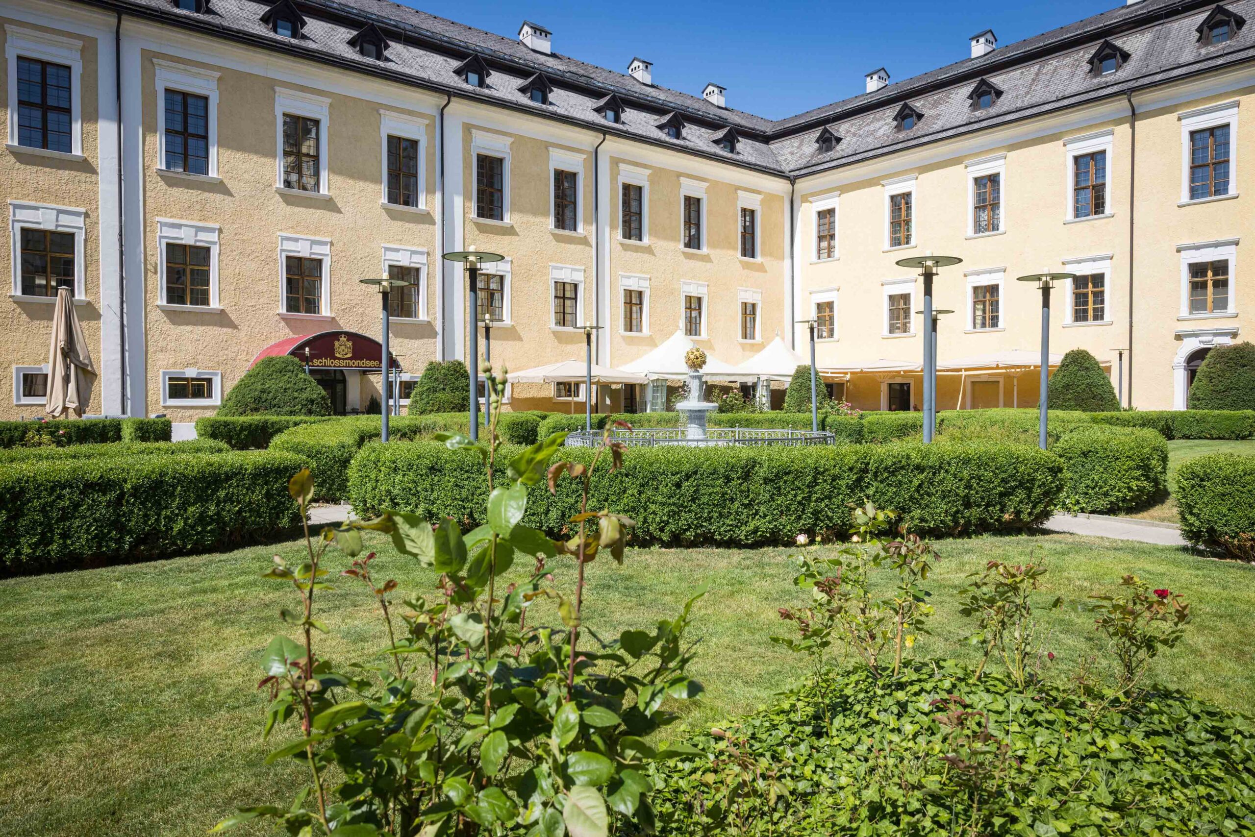 Idyllischer Schlossgarten mit Sitzgelegenheiten vor dem historischen Schlosshotel Mondsee