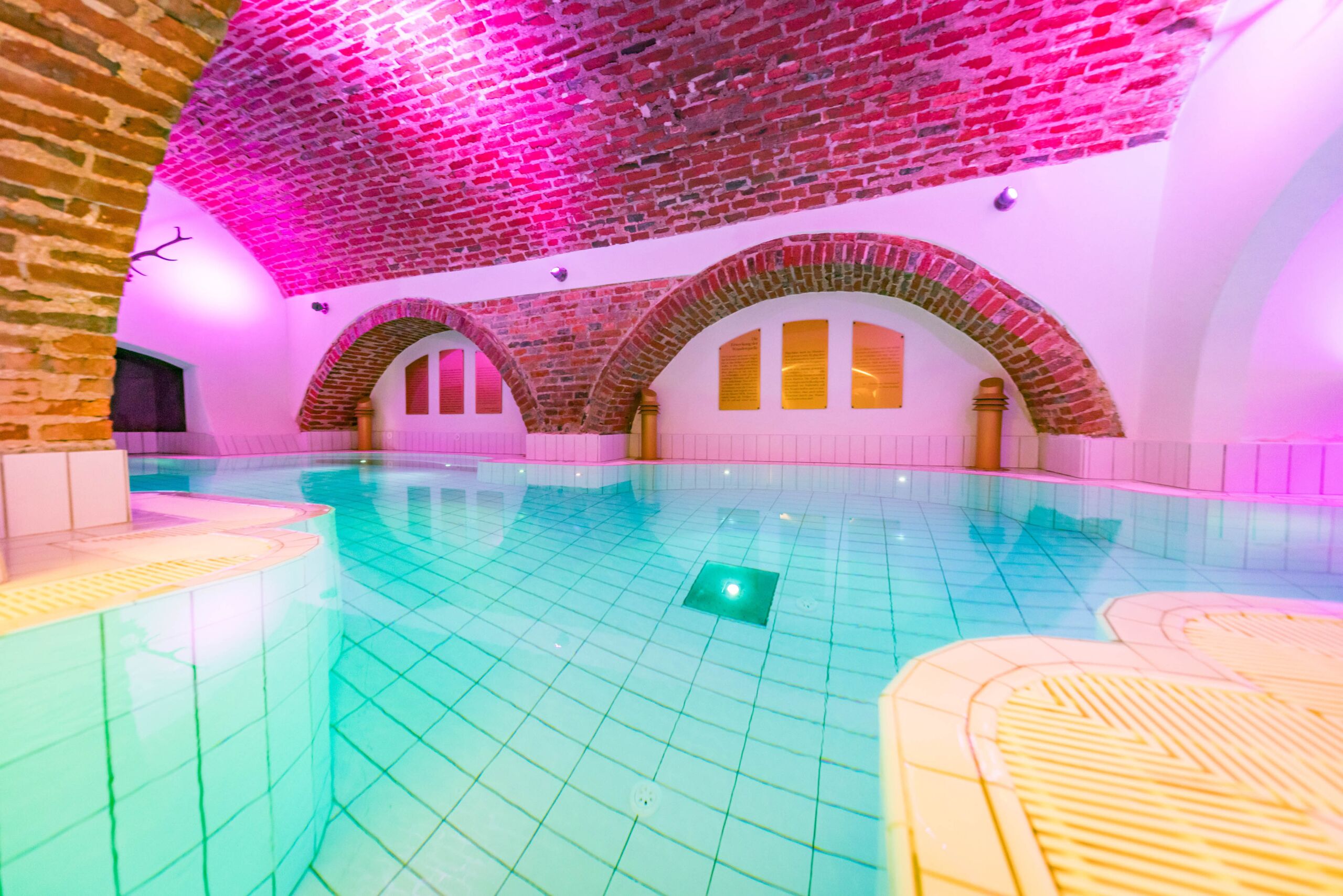 Historisches Gewölbebad mit entspannendem Wasserbereich, stimmungsvoller Beleuchtung und Wellness-Atmosphäre im Monasterium Spa des Schlosshotels Mondsee