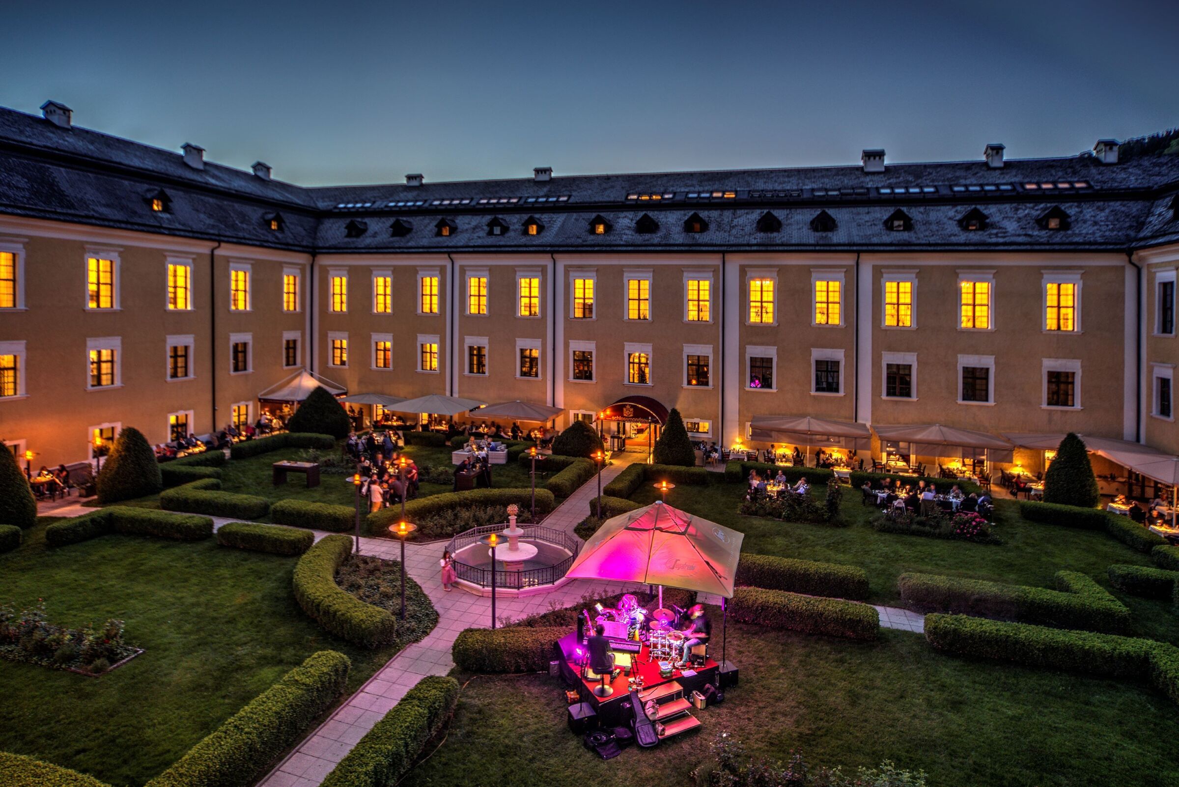 Stimmungsvolle Abendaufnahme im Schlossgarten des Schloss Mondsee mit warmem Licht und ruhiger Atmosphäre