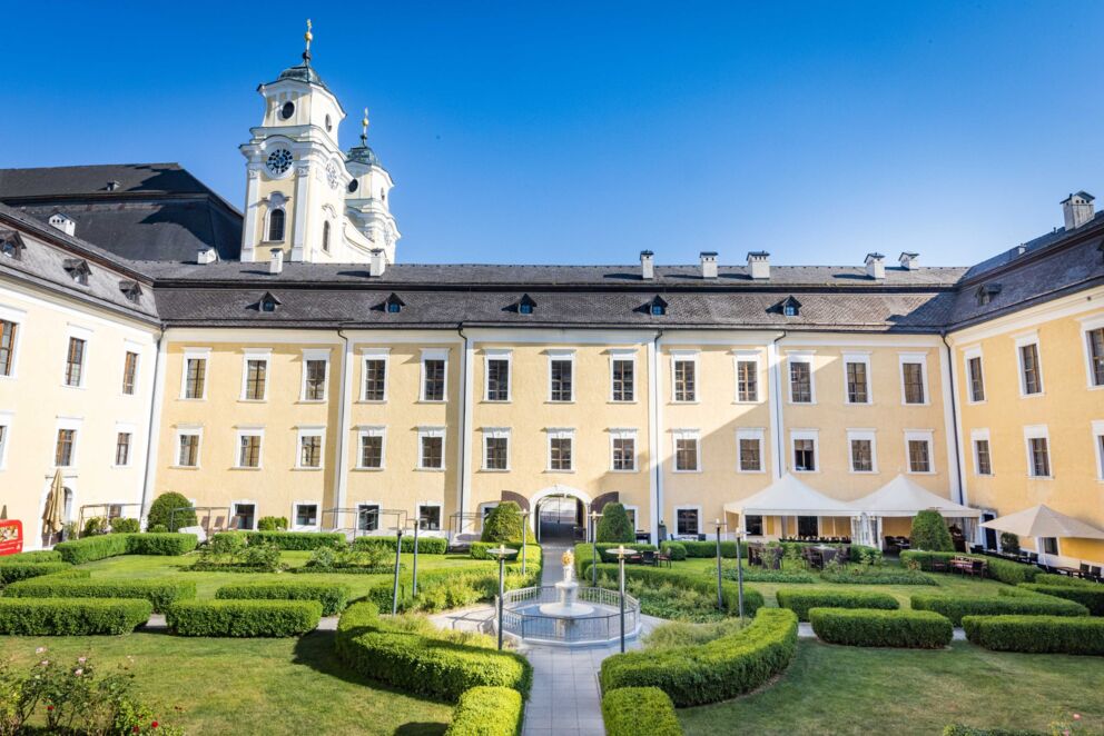 Schlossgarten des Schlosshotels Mondsee mit Blick auf die historische Basilika Kirche – idyllische Kombination aus Gartenanlage und beeindruckender Architektur